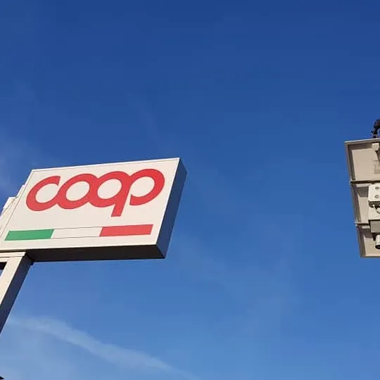 Insegna Coop su palo durante il montaggio con la gru