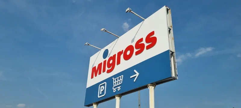 Insegna pubblicitaria Migross su palo, con le indicazioni per il parcheggio