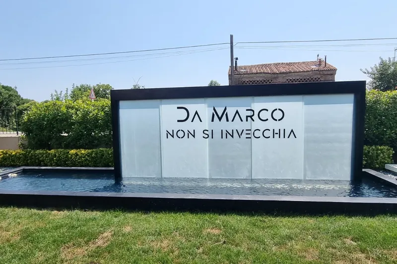 Scritta traforata DA MARCO sulla parete d'acqua della fontana in giardino