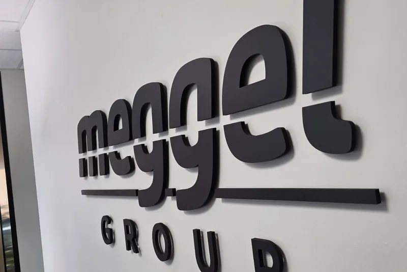 Lettere nere in rilievo meggel GROUP sulla parete di un ufficio